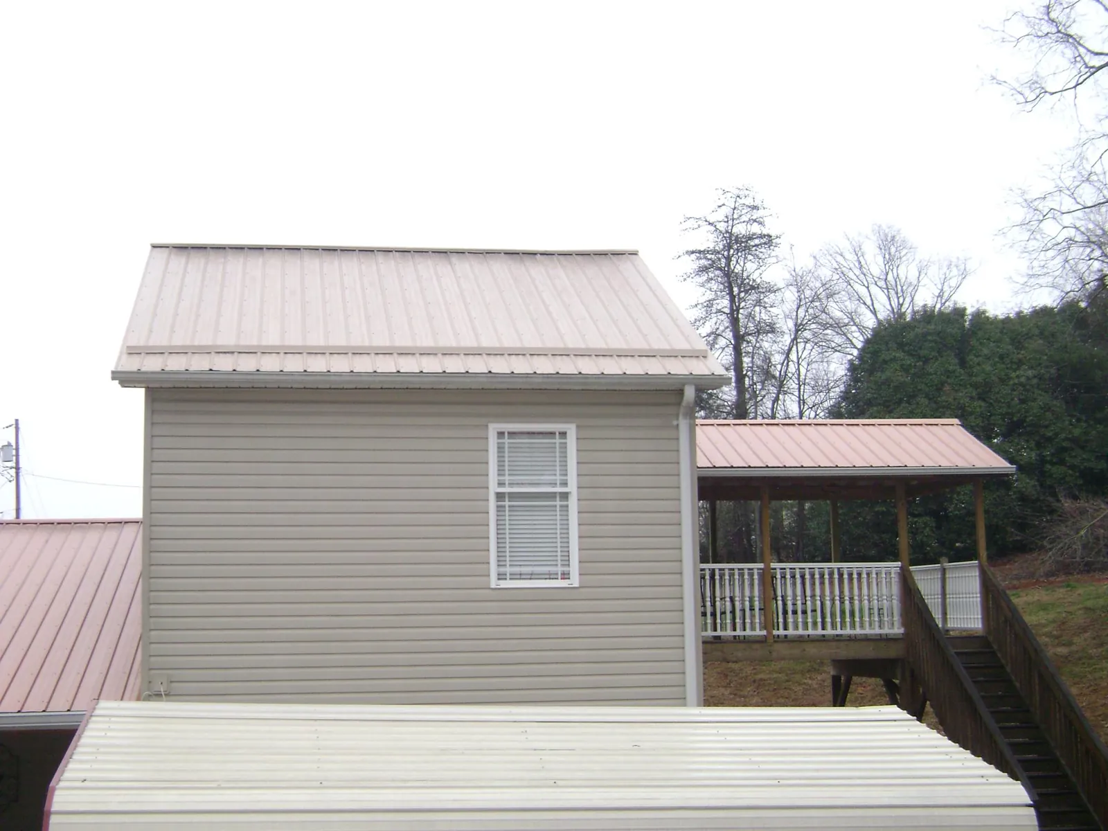 Tan metal roofs on a two story addition and attached porch, from a Roof Replacement job in Grand Junction